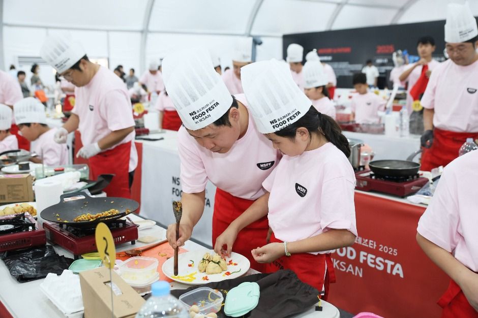 2025년 NS푸드페스타 요리경연에서 참가자들이 조리대 앞에서 접시를 완성하고 있어요.